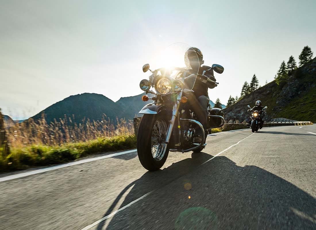 Motorcycle Insurance - Motorcycle Driver Riding Along a Scenic Highway at Dusk With Mountains in the Distance