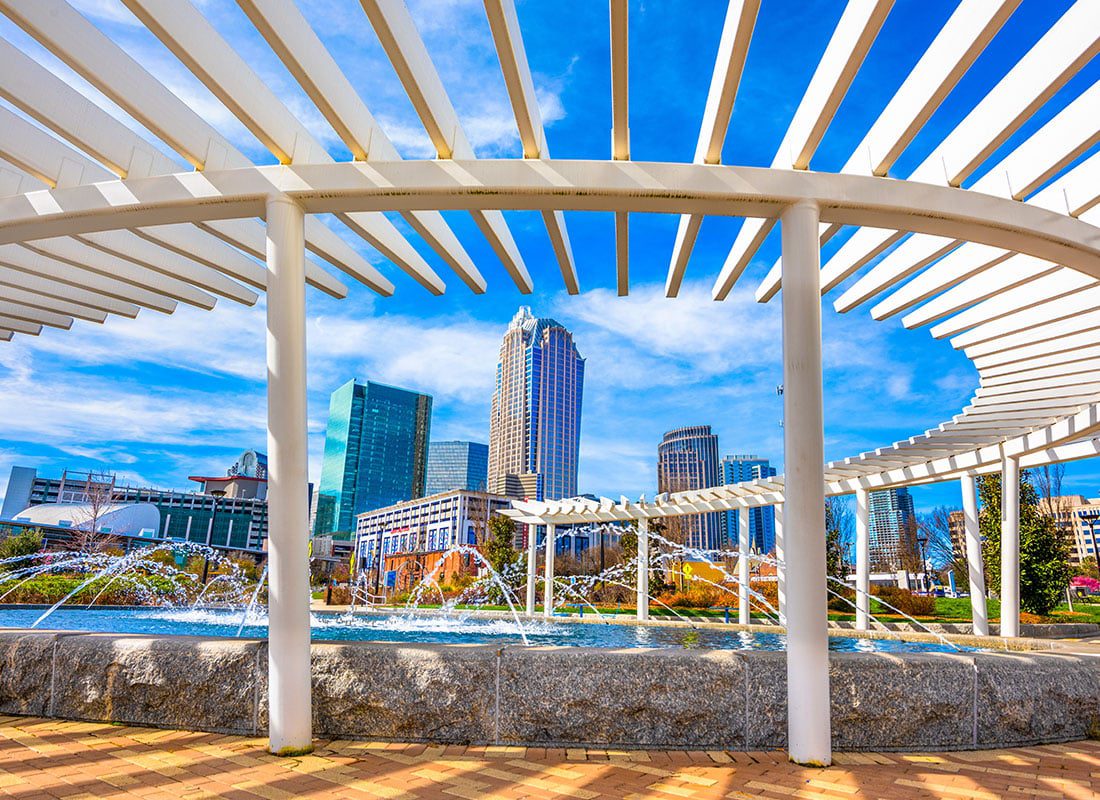 Charlotte, NC - View of a Curved Awning Next to a Fountain with Views of the Downtown Charlotte North Carolina City Skyline Against a Bright Blue Sky