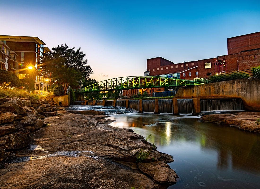 Greenville, SC - View of a Bridge Across the River Surrounded by Commercial Buildings in Downtown Greenville South Carolina at Sunset